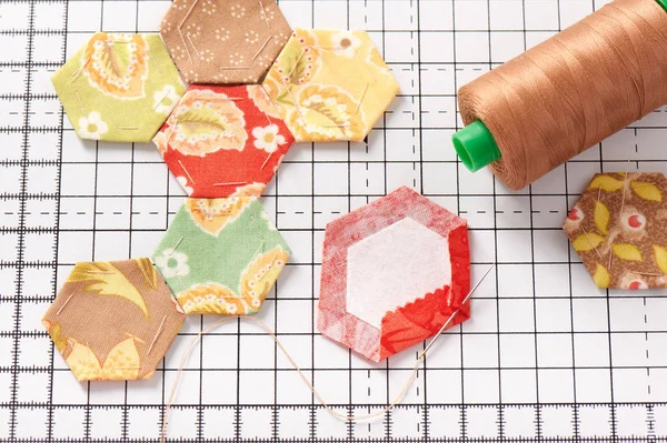 Hexagones troceados de papel inglés sobre estera artesanal blanca — Foto de Stock