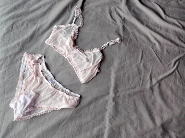 Red gift box, hearts and women's pink lingerie lying at grey bed as background — 스톡 사진