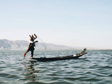 24 Şubat 2020 'de Myanmar' daki Inle Gölü 'nde balıkçılar balıkçı ağlarını çözüp teknenin kenarında güneş ışığı altında duruyorlar. Inle Gölü, Myanmar