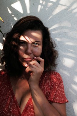 Kapalı portre, artı kırmızı elbiseli, palmiye yapraklı beyaz arka planda bir model. Vücut pozitif konsept.