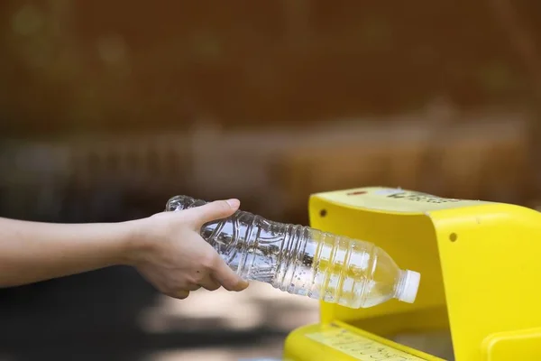 Девушка выбрасывает пластиковые бутылки в мусор для переработки — стоковое фото