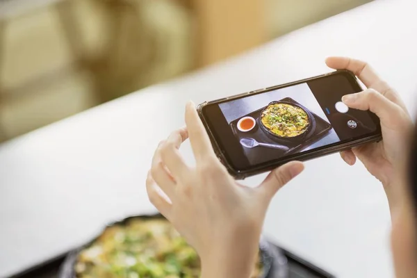 Девушка фотографирует еду со смартфона в ресторане — стоковое фото
