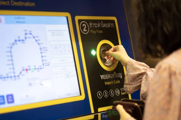 Ein mädchen steckte münze in den fahrkartenautomaten in der u-bahnstation in bangkok, thailand, 28.11.2019 — Stockfoto