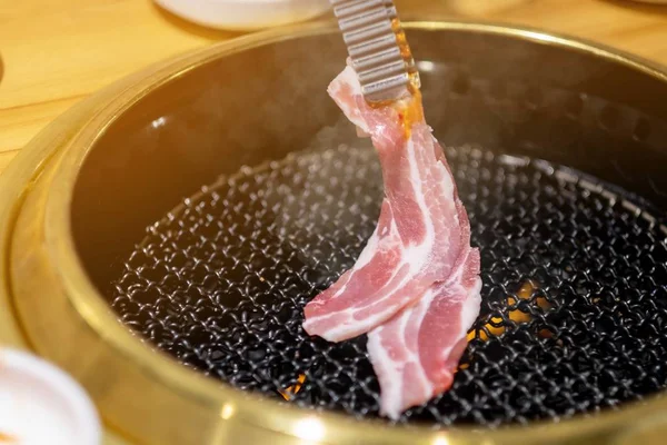 Женщина готовит свинину в корейском ресторане — стоковое фото