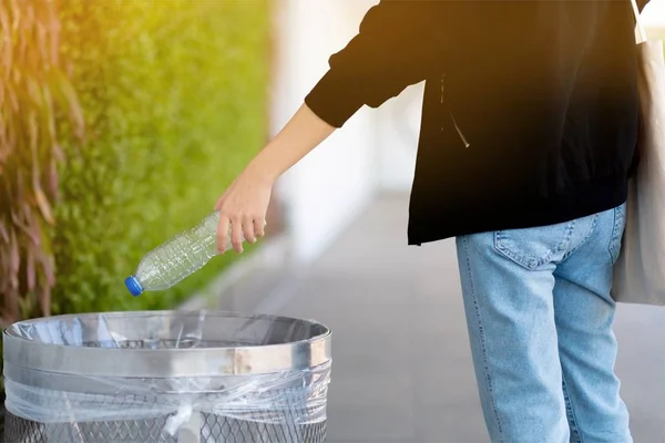 Девушка выбрасывает пластиковые бутылки в мусор для переработки — стоковое фото