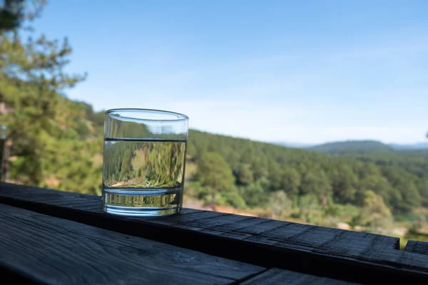 Um copo de água potável e vista montanha fundo — Fotografia de Stock