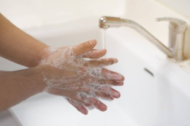Bir adam ellerini lavaboda sabunla yıkadı.