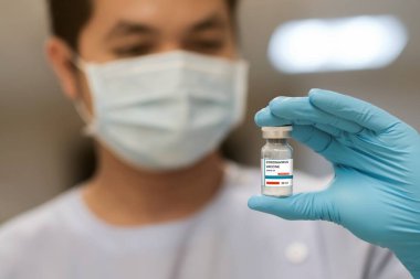Doktor ve mavi eldivenler Coronavirus aşılarını tutuyor. 