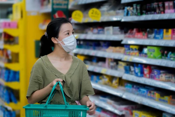 Asian women and surgical mask shopping some food in supermarket, covid-19 crisis