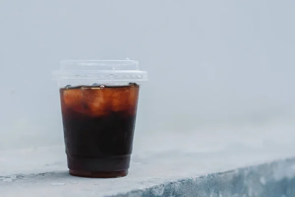 A glass of ice black coffee on white wall background
