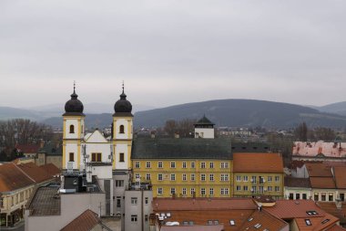 Gökyüzünde bulutlar olan güneşli bir günde kilise ve kasaba. Slovakya