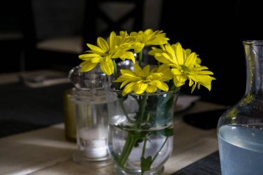 Masadaki vazoda sarı çiçekler.