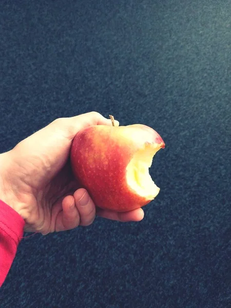 hand with an apple on a dark background