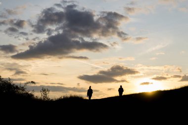 Gün batımında tarladaki insanların silueti.