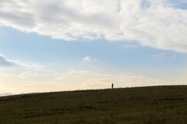 Adam güzel günbatımında tarlada yürüyor