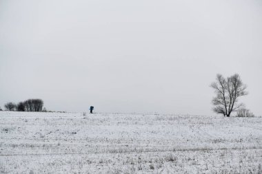 İnsanlar çıplak ağaçlarla karlı arazide yürüyorlar.