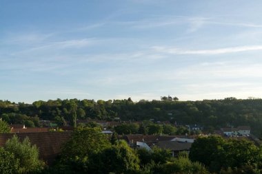 güneşli yeşil manzaralı evler ve bulutlu gökyüzü