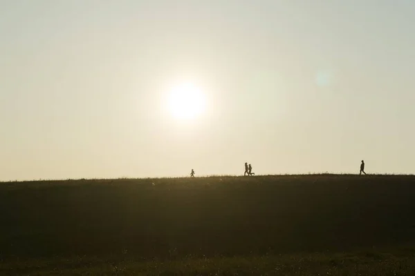 日没時に牧草地を歩く人々 — ストック写真