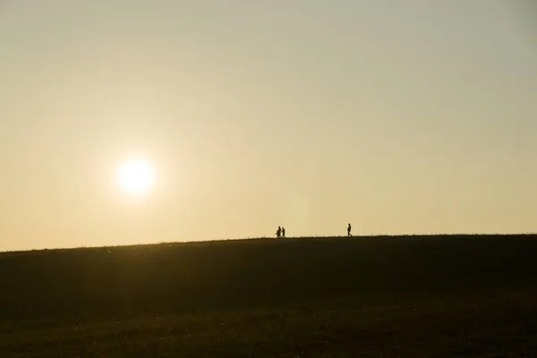 日没時に牧草地を歩く人々 — ストック写真