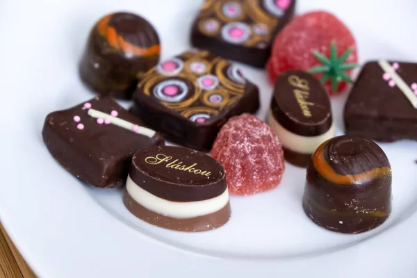 ホワイトプレートで出されるチョコレートキャンディーやお菓子 — ストック写真