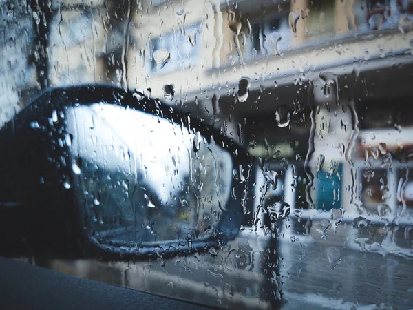 Raindrops on a car window with the mirror