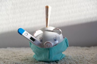 Termometresi solunum maskeli domuz kumbarası salgın sırasında ekonomik sorunları ve finansal tasarrufları gösteriyor. Slovakya