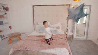 Yatak odasında yıldız şeklinde yastık tutan sevimli küçük çocuk.