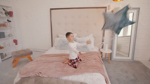 Χαριτωμένο αγοράκι πιάνει ένα μαξιλάρι σε σχήμα αστεριού στην κρεβατοκάμαρα — Αρχείο Βίντεο