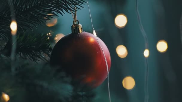 Primer plano de hermoso juguete rojo están colgando en un árbol de Navidad con luz bokeh — Vídeo de stock