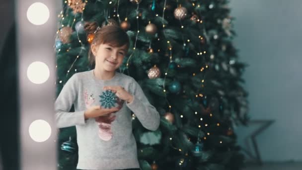 La bambina guarda il suo riflesso nello specchio. albero di Natale su uno sfondo — Video Stock