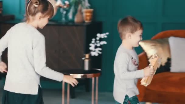 Niños alegres corriendo cerca del árbol de Navidad con un regalo — Vídeos de Stock