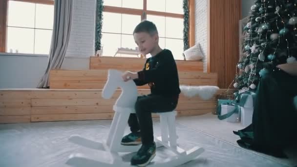 Bonito menino monta no um brinquedo cavalo — Vídeo de Stock