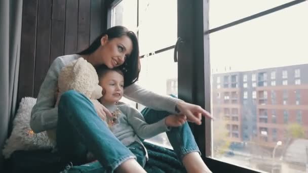Mama z synem siedzącym na parapecie i wyglądającym przez okno — Wideo stockowe