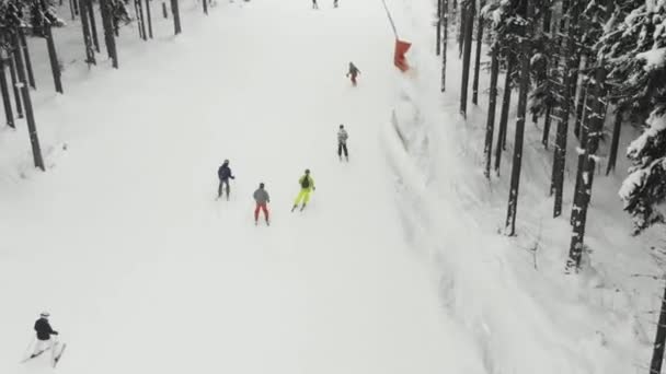 Les skieurs et les snowboarders descendent la piste dans une station de ski. Vue du dessus — Video