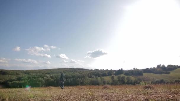 Hermoso día soleado. el hombre camina por el campo cultivado — Vídeos de Stock