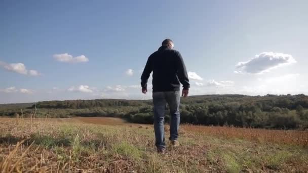 Um fazendeiro homem caminha pelo campo no dia ensolarado — Vídeo de Stock