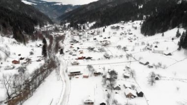 Aerial shot of a mountain valley with settlement and road placed between steep alpine slopes