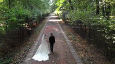 Sonbahar parkında yürüyen ve konuşan olgun beyaz bir çiftin arka görüntüsü..