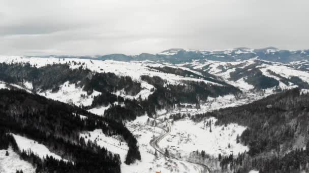 Scatto aereo di una valle montana con insediamento e strada posta tra ripidi pendii alpini — Video Stock