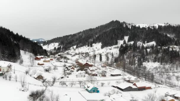 Aerial shot of a mountain valley with settlement and road placed between steep alpine slopes — Stock Video