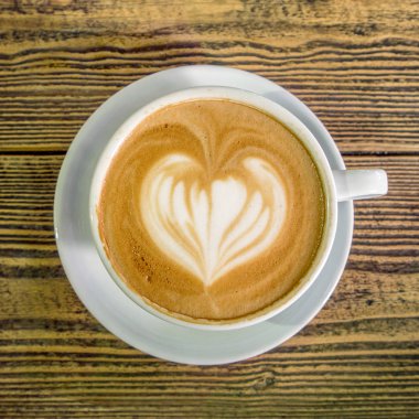 Ahşap arka plan üzerinde plaka ile hizmet kalp sütlü kahve Üstten Görünüm.