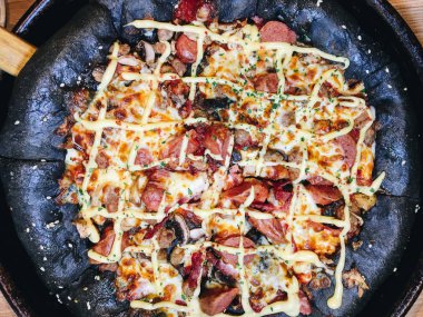 Siyah hamurlu, sosisli ve peynirli olağandışı pizza..