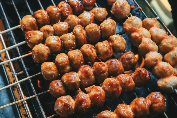 Cooking meatballs on skewers on grill outdoor