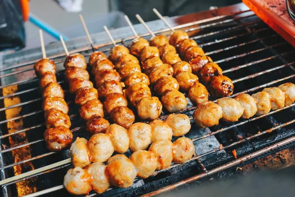 Cooking meatballs on skewers on grill outdoor