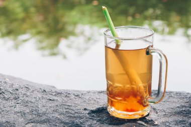 Kocaman bir taşın üzerinde duran bir bardak limonata.