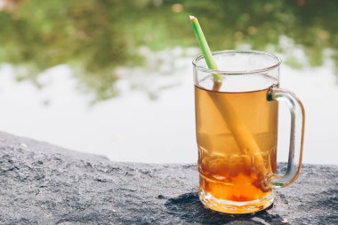 Kocaman bir taşın üzerinde duran bir bardak limonata.