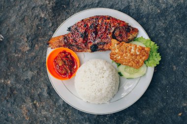 Lezzetli bir tabak pilav, füme balık ve dilimlenmiş salatalık ve salata ile sos.