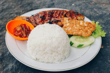 Lezzetli bir tabak pilav, füme balık ve dilimlenmiş salatalık ve salata ile sos.