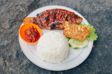 Lezzetli bir tabak pilav, füme balık ve dilimlenmiş salatalık ve salata ile sos.