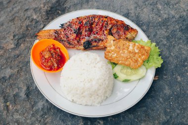 Lezzetli bir tabak pilav, füme balık ve dilimlenmiş salatalık ve salata ile sos.